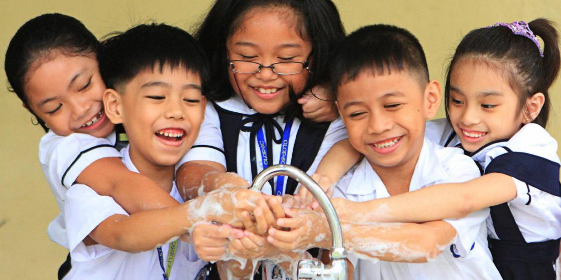 School children in the Philippines wash their hands together at a sink. 