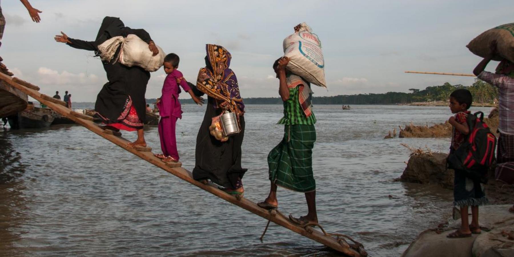 Climate-affected internally displaced persons board a boat to travel to Dhaka, Bangladesh.